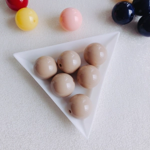 Close-up of beige acrylic round beads for DIY jewelry with glossy finish and threading holes