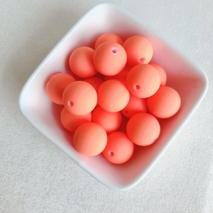 Vue macro de perles rondes macaron orange corail mat avec trou central pour DIY