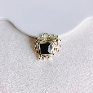 Detailed view of heart-shaped gold pendant with irregular lava texture and black gemstone