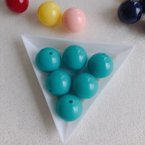 Macro detail of teal acrylic round beads with holes for DIY jewelry making and crafts