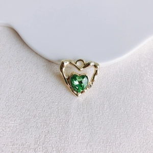Vue macro du pendentif cœur doré avec cristal vert émeraude et détail de diamant fin
