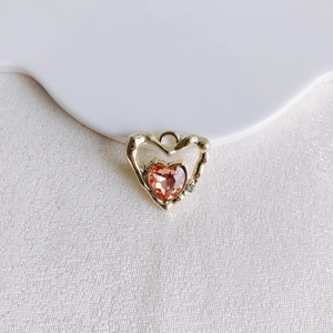 Détail du pendentif en forme de cœur avec pierre rose et bordure dorée pour bijoux artisanaux