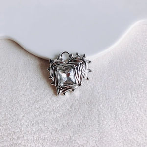 Detailed view of silver heart pendant with square zircon and irregular thorny texture