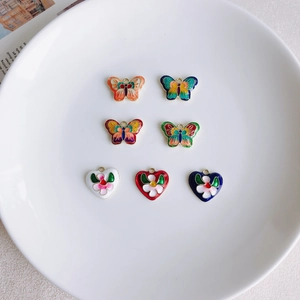 Détail macro de sept breloques en émail coloré en forme de papillon et de cœur pour DIY