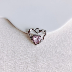 Détail macro du pendentif cœur en métal argenté avec incrustation de pierre rose