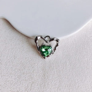 Détail du pendentif cœur en argent avec pierre précieuse verte et cadre ajouré
