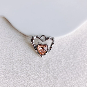 Détail macro d'un pendentif cœur en argent avec une pierre orange ambre en forme de cœur