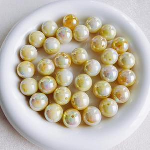 Macro-opname van 16mm AB iriserende crème gele acryl kralen in een witte schaal