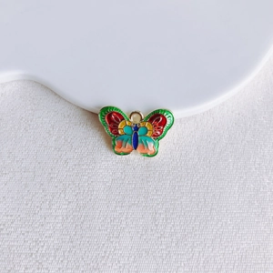 Vue macro d'un pendentif papillon en émail coloré avec contours dorés pour bijoux DIY