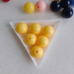 Macro view of bright yellow acrylic round beads with center hole on white tray