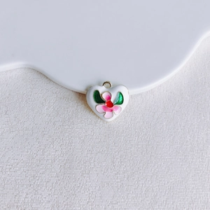 Détail d'un pendentif coeur blanc avec fleur rose et feuilles vertes en émail