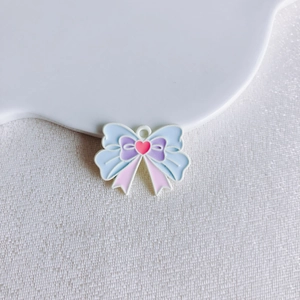 Macro detail of enamel bow pendant with heart motif and pastel colors for jewelry making