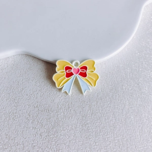 Detailed view of yellow enamel butterfly bow charm with red center and pink heart