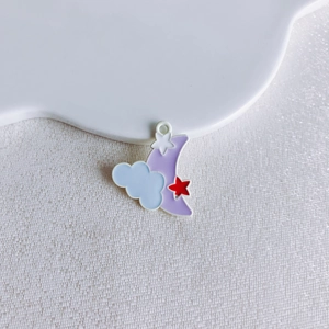 Macro detail of alloy moon and star charms for DIY jewelry on white cloud tray
