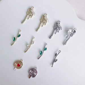 Dettaglio di ciondoli a cuore in metallo e charms a foglia color smeraldo lucido
