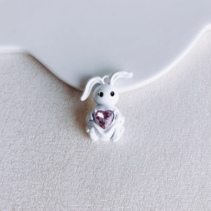 Nahaufnahme eines weißen Hasen-Anhängers mit rosa Herz-Edelstein für DIY-Schmuck
