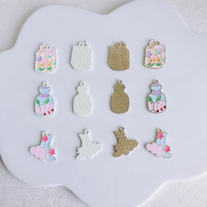 DIY alloy enamel pendants with peach milk and celestial designs on a cloud display board