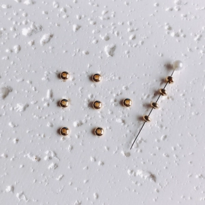 Macro shot of 14K gold-filled spacer beads on a pin with smooth metallic finish