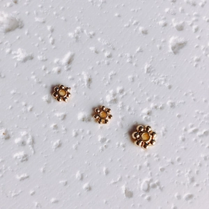 Macro detail of 14K gold filled snowflake spacer beads for DIY jewelry making