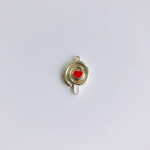 Dettaglio del ciondolo a lecca-lecca dorato con cuore rosso e smalto bianco