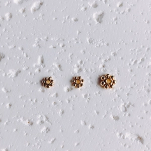 Macro shot of three 14K gold-filled snowflake spacer beads for DIY jewelry making