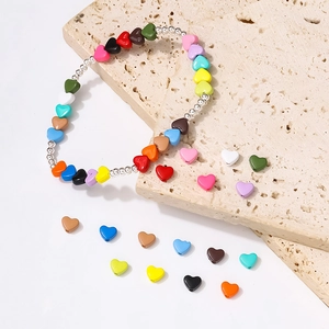 Handmade colorful heart bead bracelet with silver round beads on a beige stone surface