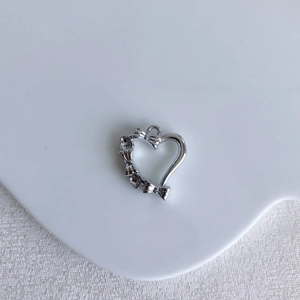 Close-up of a silver hollow heart pendant with a bow detail for DIY jewelry making