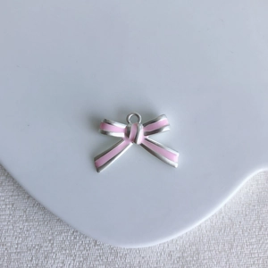 Detailed view of a pink enamel bow pendant with silver edges for DIY jewelry making