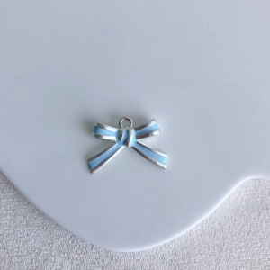 Macro shot of silver bow pendant with light blue enamel and metal ring detail