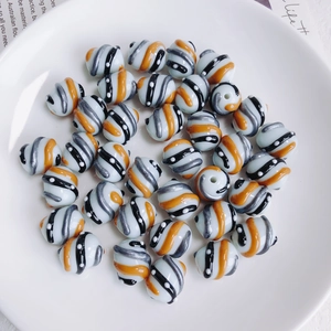 Macro-opname van gestreepte acryl kralen met oranje spiralen in een keramische schaal