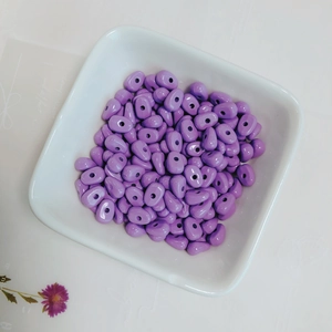 Close-up of purple glazed irregular teardrop beads for DIY jewelry making in a ceramic tray