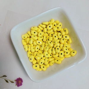 Macro shot of bright yellow oval spacer beads for handmade jewelry in a white tray