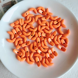 Close-up of orange acrylic wheat ear beads for DIY jewelry making in a white ceramic dish