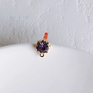Detailed macro view of a purple round cubic zirconia stone in a golden metal prong setting