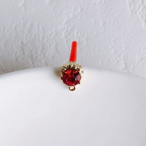 Detail of red faceted gemstone pendant with gold metal base and small hanging loop
