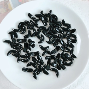 Macro shot of glossy black V-shaped acrylic beads for DIY jewelry and phone chains