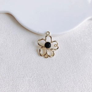 Détail d'un pendentif fleur doré avec pierre noire pour la création de bijoux DIY