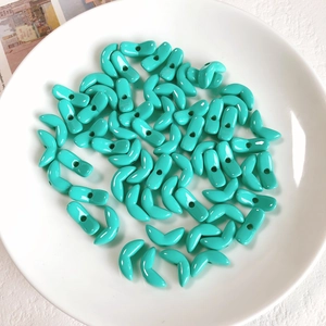 Macro detail of turquoise V-shaped acrylic beads with glossy finish for DIY jewelry