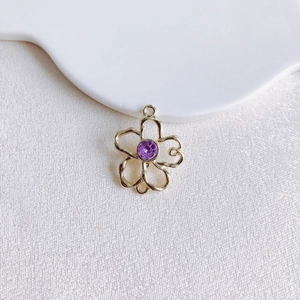 Vue macro du pendentif fleur en alliage doré avec cristal violet pour bijoux DIY