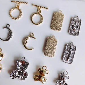 Golden and silver mini DIY charms including teddy bears, moons, and textured pendants