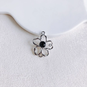 Gros plan détaillé d'un pendentif fleur argenté avec gemme noire pour bijoux