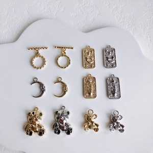 Detailed view of DIY moon and bear charms set in gold and silver on a white tray