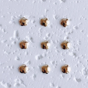 Close-up of golden five-petal flower bead spacers in a 3x3 grid for DIY jewelry making