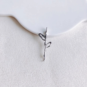 Macro d'un pendentif rose en argent à texture fondue sur un plateau céramique