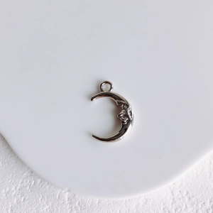 Detail shot of silver moon pendant with man-in-the-moon relief on white tray