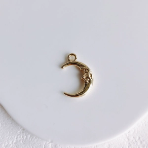 Detailed view of a golden crescent moon face charm for DIY jewelry making and craft projects