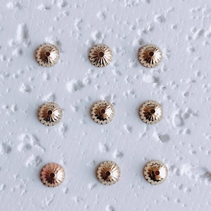 Macro detail of nine 18K gold plated flower bead caps for DIY jewelry necklace making