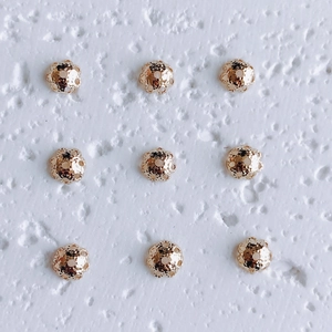 Macro detail of nine 18K gold plated hollow floral spacer beads for jewelry making