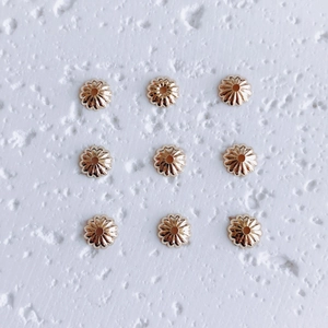 Macro shot of 9 gold flower-shaped spacer beads for DIY jewelry making and necklace crafts