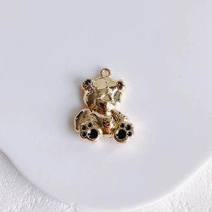 Macro shot of gold mini bear pendant with black enamel details for jewelry making